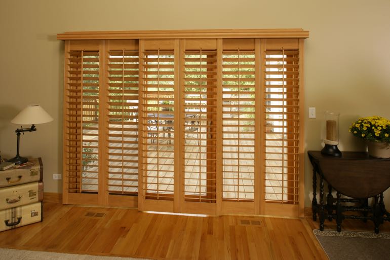 Wood shutters on sliding door leading to outdoor porch.